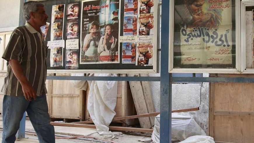 A resident walks at the entrance of a cinema in Baghdad April 26, 2011. Iraq once had 82 cinemas, 64 of them located in the teeming capital, home to about 7 million of Iraq's 30 million people. One by one, they closed during the Saddam era, when the government controlled the selection and importation of films, until only five remained at the time of the invasion. The insurgency that followed and killed tens of thousands of people made Iraqis afraid of being in public places and crowds. They chose the relati