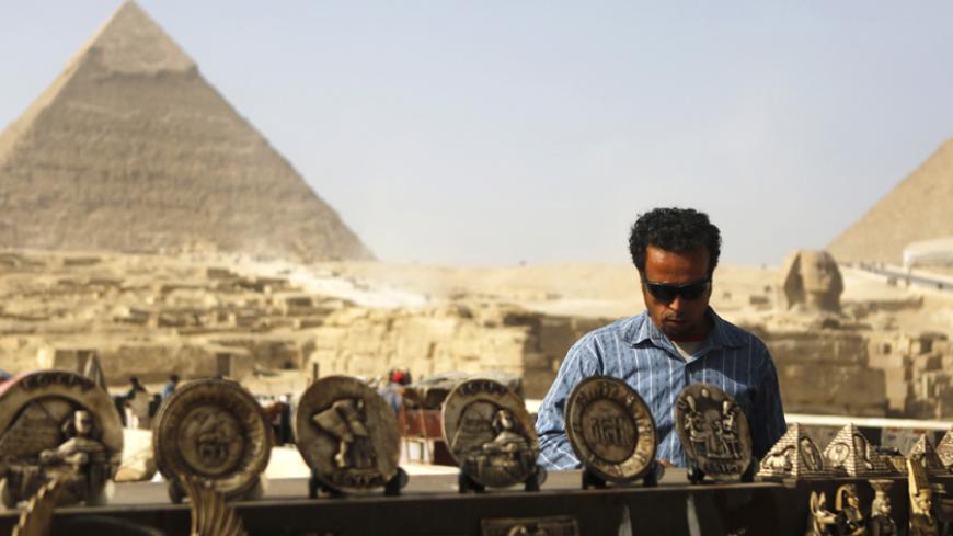 A souvenirs vendor waits for tourists in front of the Sphinx and the Giza Pyramids on the outskirts of Cairo, December 9, 2014. Egypt's tourism revenues jumped 112 percent to about $2 billion in the third quarter of 2014, a tourism ministry official said, suggesting the key industry was showing signs of recovery, albeit from a particularly bad third quarter last year. Tourism, an important source of foreign currency, has been hammered since the popular uprising that toppled Hosni Mubarak in 2011. REUTERS
