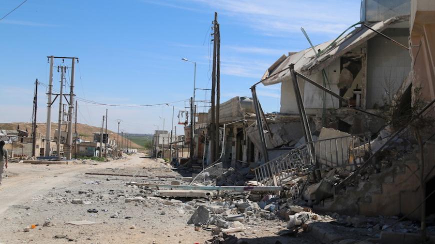 A man walks near damaged houses after Syrian rebels and the al Qaeda-affiliated Nusra Front took control of al-'Iss town, in Aleppo countryside, Syria April 2, 2016. REUTERS/Ammar Abdullah - RTSDAHL