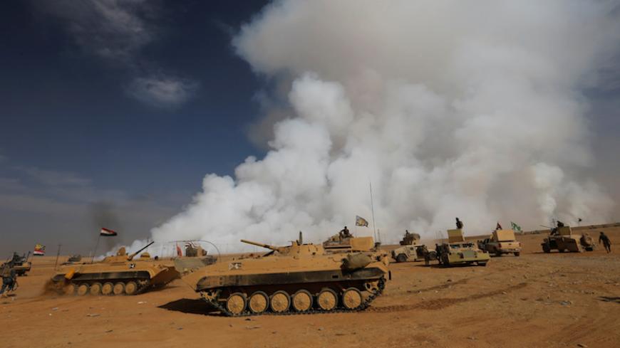 REFILE - ADDITIONAL CAPTION INFORMATIONIraqi army gather after the liberation of a village from Islamic State militants, south of Mosul, during an operation to attack Islamic State militants in Mosul, Iraq, October 21, 2016, as toxic smoke is seen over the area after Islamic State militants set fire to a sulphur factory. REUTERS/Thaier Al-Sudan     TPX IMAGES OF THE DAY - RTX2PXNT