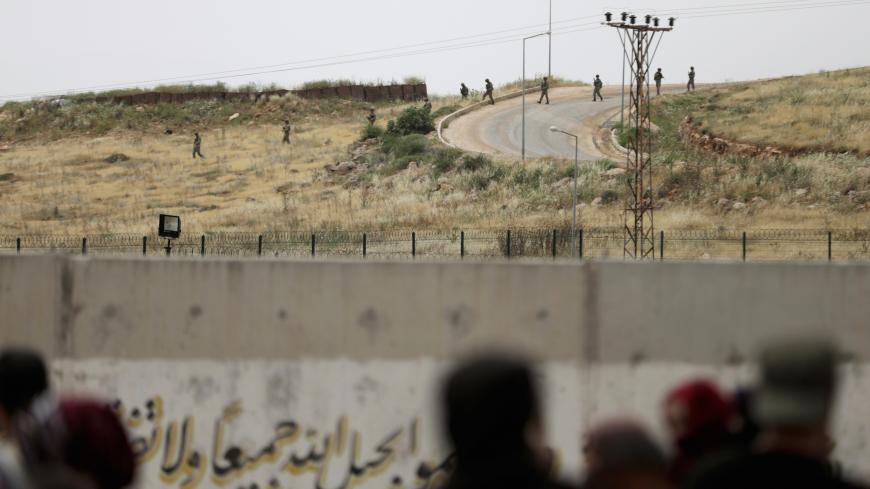 Turkish soldiers walk at the Atmeh crossing on the Syrian-Turkish border, as seen from the Syrian side, in Idlib governorate, Syria May 31, 2019. REUTERS/Khalil Ashawi - RC17B93A8C20
